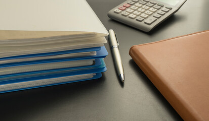 piled up files, pen, calculator and notebook on the table