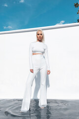Beautiful fashion girl posing in white clothes in the studio while standing in the water