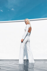 Beautiful fashion girl posing in white clothes in the studio while standing in the water