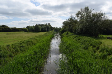 Obraz premium River way running between two large green hills in the British country.