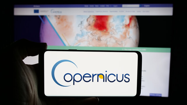 Stuttgart, Germany - 2024-10-10: Person holding cellphone with logo of ESA Earth observation project Copernicus on screen in front of webpage. Focus on phone display.