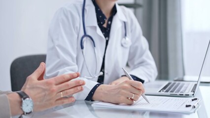 Doctor and patient are talking in clinic after health check up. Female physician is making notes. Medicine concept