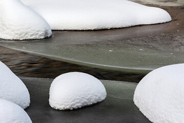 Tranquil Winter Scene: Close-Up of Fresh Snow on Rocks in Riverbed - Ideal Background Image for Seasonal Themes