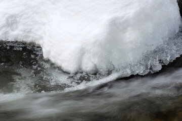 Tranquil Winter Scene: Close-Up of Fresh Snow on Rocks in Riverbed - Ideal Background Image for Seasonal Themes