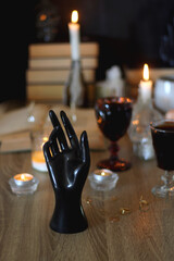 Books, lit candles, red wine, snacks and various deocration on the table. Dark academia or Halloween concept. Selective focus.