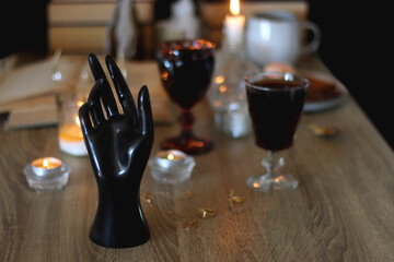 Books, lit candles, red wine, snacks and various deocration on the table. Dark academia or Halloween concept. Selective focus.