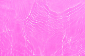 Pink water bubbles on the surface ripples. Defocus blurred transparent pink colored clear calm water surface texture with splash and bubbles. Water waves with shining pattern texture background.