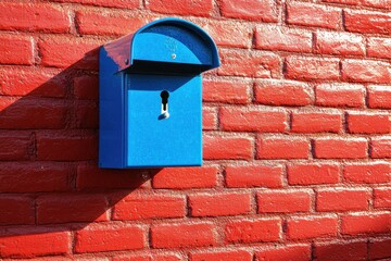 A vibrant blue mailbox mounted on a textured red brick wall, designed for collecting mail.