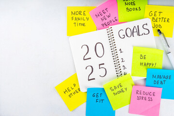 2025 Goals New Year resolution concept. Planning new year goals in notepad and on bright colorful paper stickers, plan listing of new beginnings goals, resolutions setting
