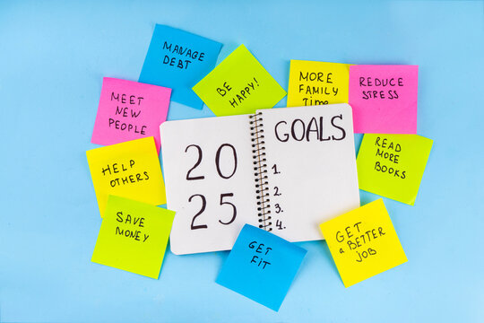2025 Goals New Year resolution concept. Planning new year goals in notepad and on bright colorful paper stickers, plan listing of new beginnings goals, resolutions setting