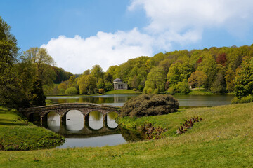 Reflections of the five arched bridge in the water of the lake at Stourhead Park in Warminster Wiltshire England UK