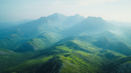Fototapeta premium The mountains are covered in lush green trees and the sky is clear and blue. The scene is peaceful and serene, with the mountains providing a beautiful backdrop