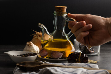 Fotografía de una botella de aceite de oliva junto a ingredientes frescos como ajo, cebolla y especias. Perfecta para representar la esencia de la cocina mediterránea y el uso de productos naturales y