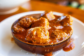 Plato de albóndigas en una rica salsa tradicional servidas en un recipiente de barro. Ideal para transmitir la esencia de la comida casera y el sabor auténtico de la cocina mediterránea.