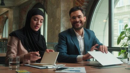 Multiracial business Arabian man muslim woman in hijab two colleagues male female satisfied businessman businesswoman finish accomplish laptop work close notebook done end day relax walk go out office