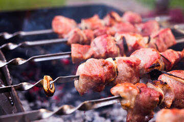 Cooking, barbecue and food concept close up of shish kebab meat on skewers roasting on brazier grill