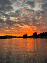 sunset over the harbor, silhouettes of ships. 