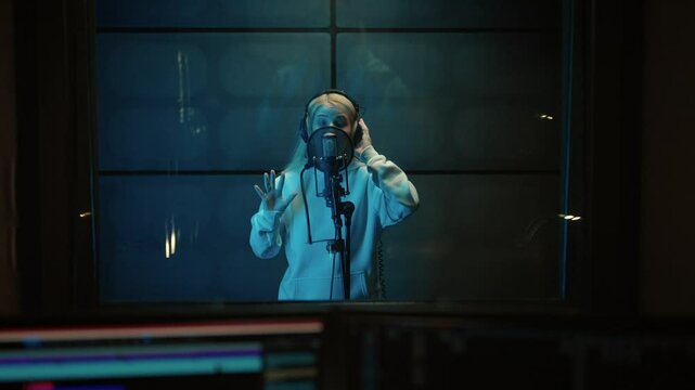 Medium portrait of talented woman singer in modern recording studio, singing hit . Musical production and record label, profession and creative hobby, blonde girl recording her first single for album