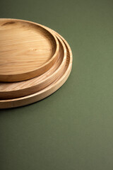 Wooden flat plates on a green background. The concept of ecological tableware. Products for modern kitchen. Zero emissions.