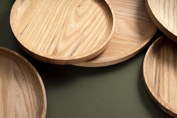 Wooden flat plates on a green background. The concept of ecological tableware. Products for modern kitchen. Zero emissions.