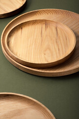 Wooden flat plates on a green background. The concept of ecological tableware. Products for modern kitchen. Zero emissions.