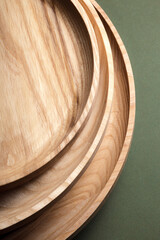 Wooden flat plates on a green background. The concept of ecological tableware. Products for modern kitchen. Zero emissions.