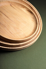 Wooden flat plates on a green background. The concept of ecological tableware. Products for modern kitchen. Zero emissions.