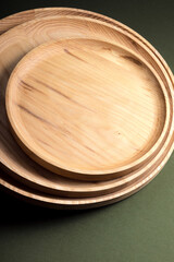 Wooden flat plates on a green background. The concept of ecological tableware. Products for modern kitchen. Zero emissions.