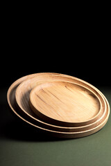 Wooden flat plates on a green background. The concept of ecological tableware. Products for modern kitchen. Zero emissions.