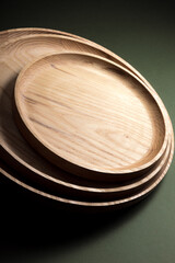 Wooden flat plates on a green background. The concept of ecological tableware. Products for modern kitchen. Zero emissions.