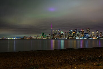 Toronto skyline at night from Toronto Ward Island, Cityscape view of the whole downtown buildings with the Ontario river on the foreground reflecting the skyscrapers lights