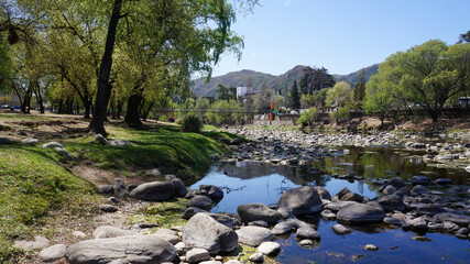 Landscape view of Santa Rosa river going trough Calamuchita small town. Large green trees in both sides