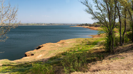 Landscape view of the shore of "Embalse Rio tercero" reservoir, surrounded by a green trees forest