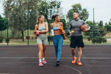 Fototapeta premium Active, multinational group of friends walking, training together on the street holding sport mat