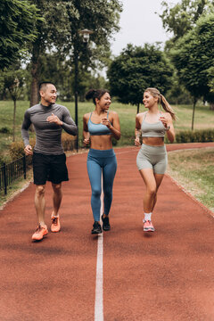Diverse group of happy sportswomen and man wearing stylish sportwear running, training together