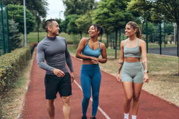 Group of multinational people, African American and Caucasian women and Asian man, runners walking