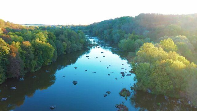 River with rapids. Beautiful fall nature by the river. River and rapids in the sunlight at sunset. Reflection of the sky and trees in the water. Aerial view.