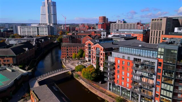 Aerial video of Leeds skyline featuring river Aire and a footbridge 