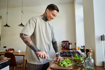 A handsome young man smiles as he chops fresh vegetables in a bright and inviting kitchen.