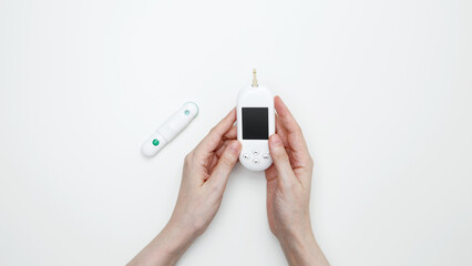 Female hands holding glucometer for measuring blood glucose levels,  lancet. Concept of worldwide diabetes awareness