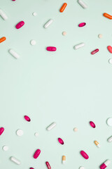 Various colorful pills and capsules scattered on a light blue background. Concept of medicine, healthcare, and pharmaceutical industry
