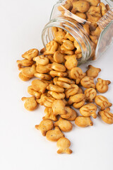 Fish-shaped  crackers spilling out of the jar isolated on white background