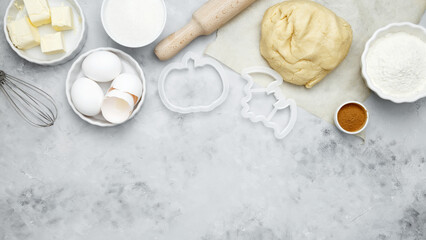 Baking ingredients including flour, butter, sugar, spices, eggs and pumpkin arranged on a gray background. Seasonal autumn baking