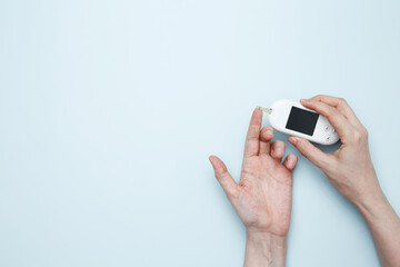 Woman hands holding glucometer for measuring blood glucose levels,  lancet. Concept of worldwide...
