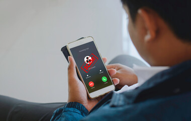 Close-up of a person holding a smartphone showing an incoming scam call warning from an unknown number.