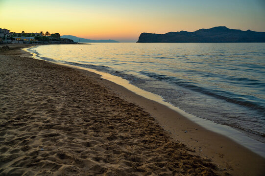 Evening illumination of sky, empty beach, sea and island of St. Theodora in Kato Stalos, Crete.