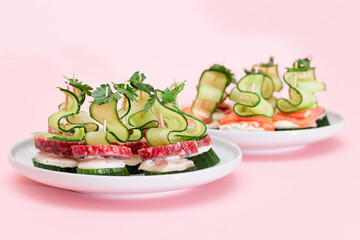 Canapes without Bread with Fresh Salmon, Salami, Cucumber, Greens and Cream Cheese on White Plate - Isolated on White. Easy Breakfast. Diet Food. Quick and Healthy Sandwiches and Snacks