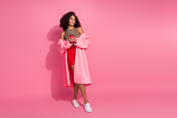 Full length photo of young lady drink coffee look empty space dressed stylish leopard print warm coat garment isolated on pink background