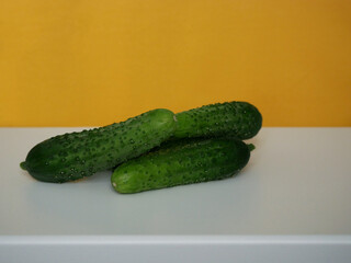 Small fresh young cucumbers at yellow background