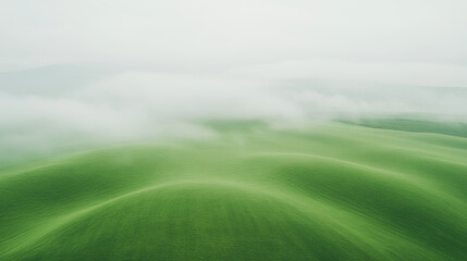 Obraz premium Lush green hills covered in soft mist create serene and tranquil landscape. gentle curves of terrain evoke sense of calm and connection to nature
